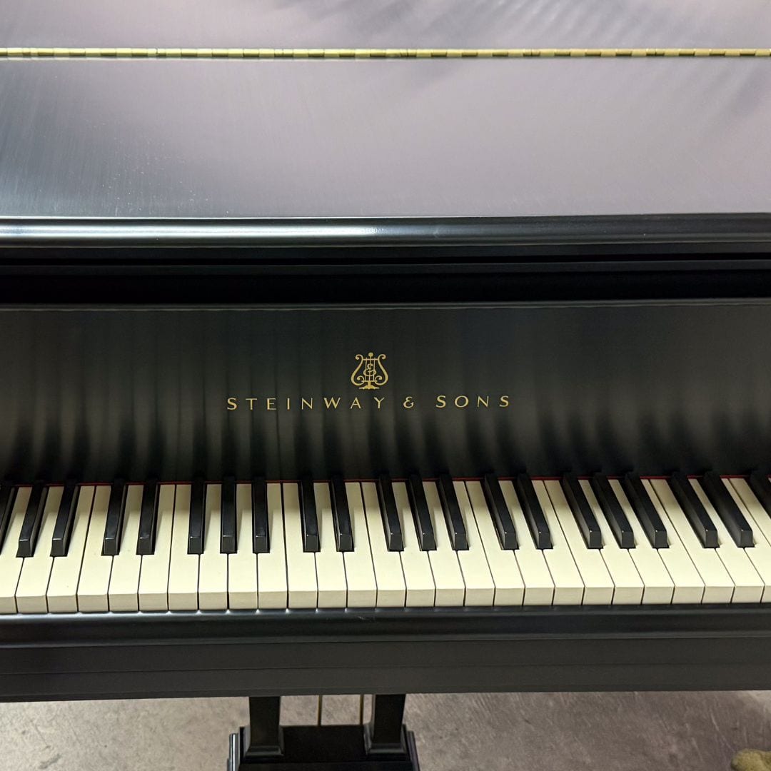 The restored Steinway Model M keyboard straight on, with the gold Steinway & Sons decal and brass pedal lyre